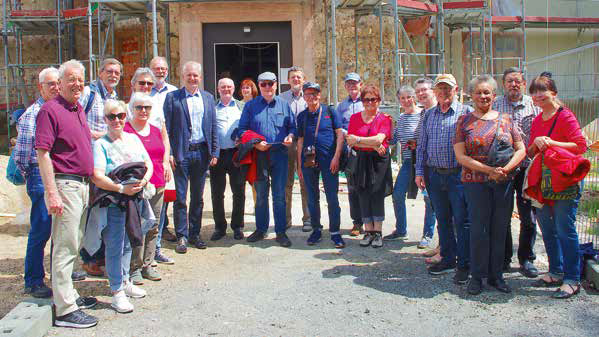 Das Foto zeigt 15 Ehemalige, die sich 2019 mit Bürgermeister Andreas Weiher und Stadtführer Otto Fiegler vor dem im Bau befindlichen Schloss versammelt haben. Foto. DED